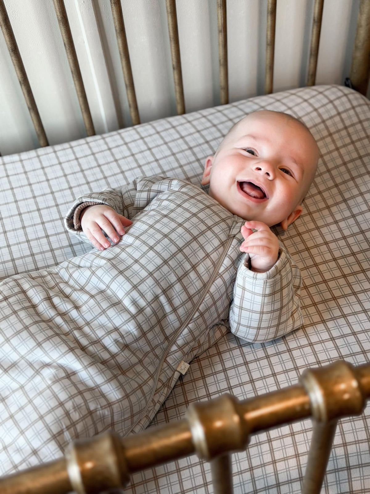 Plaid long-sleeve swaddle sack with baby face and hands visible in grid pattern