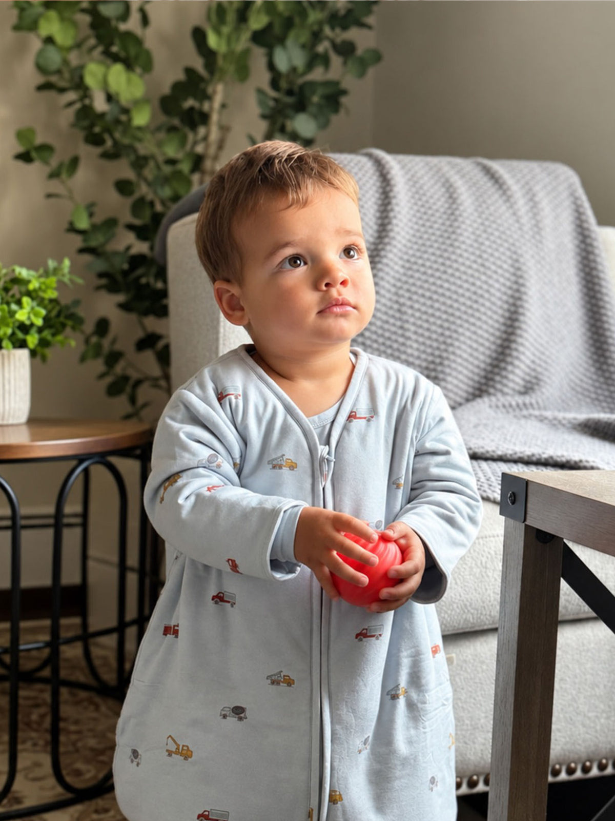 Light gray long-sleeve footed sleep sack with vehicle print and front zipper
