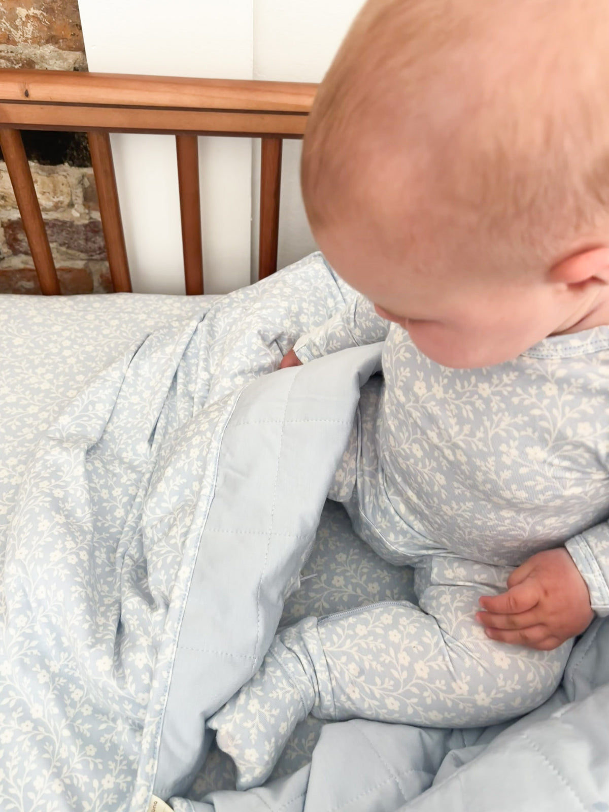 Baby cloud blanket with light blue floral print, folded front hood and zipper detail