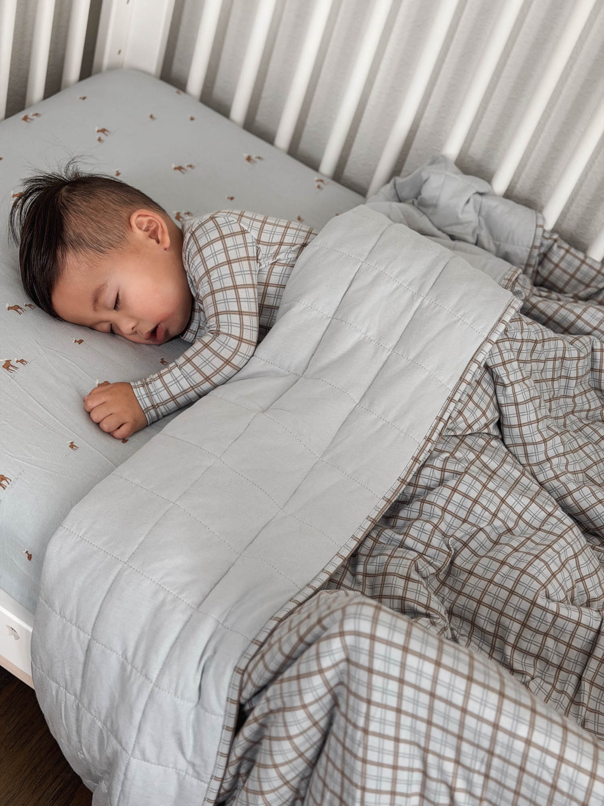 Quilted plaid baby blanket with gray-and-cream check design and stitched panels