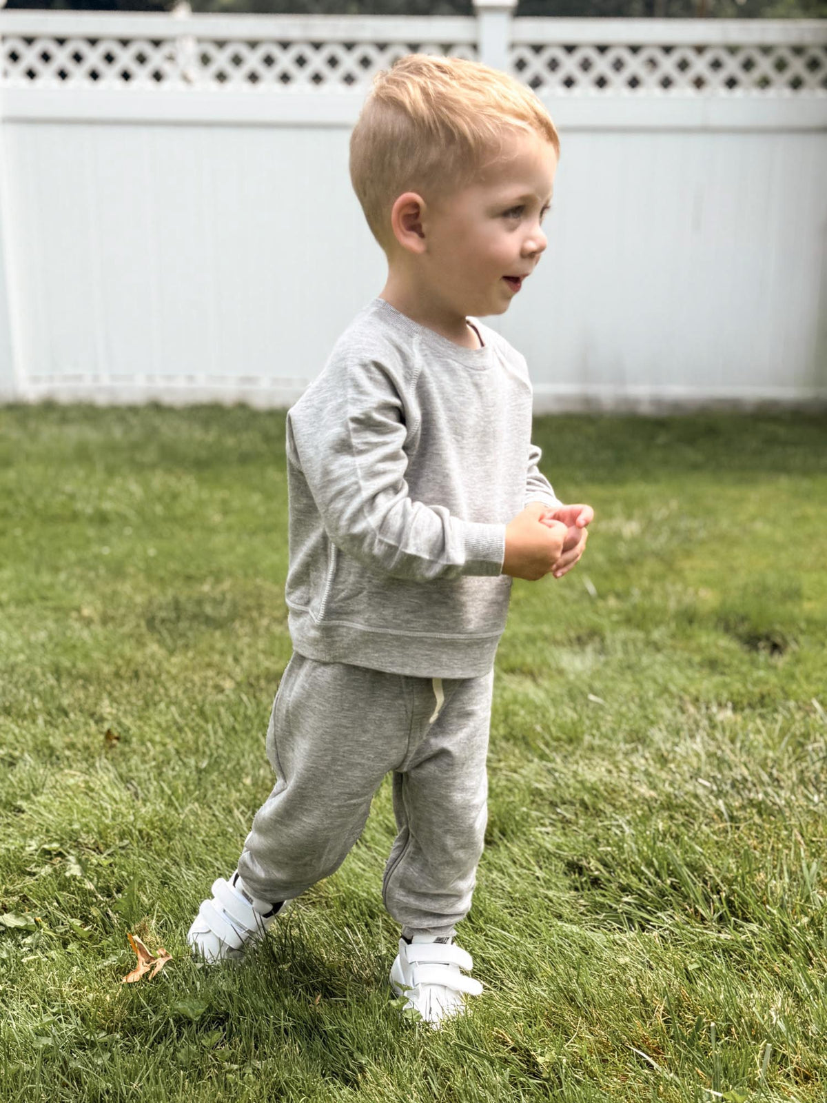 Heather grey fleece toddler sweatsuit, sweatshirt and jogger pants shown outdoors
