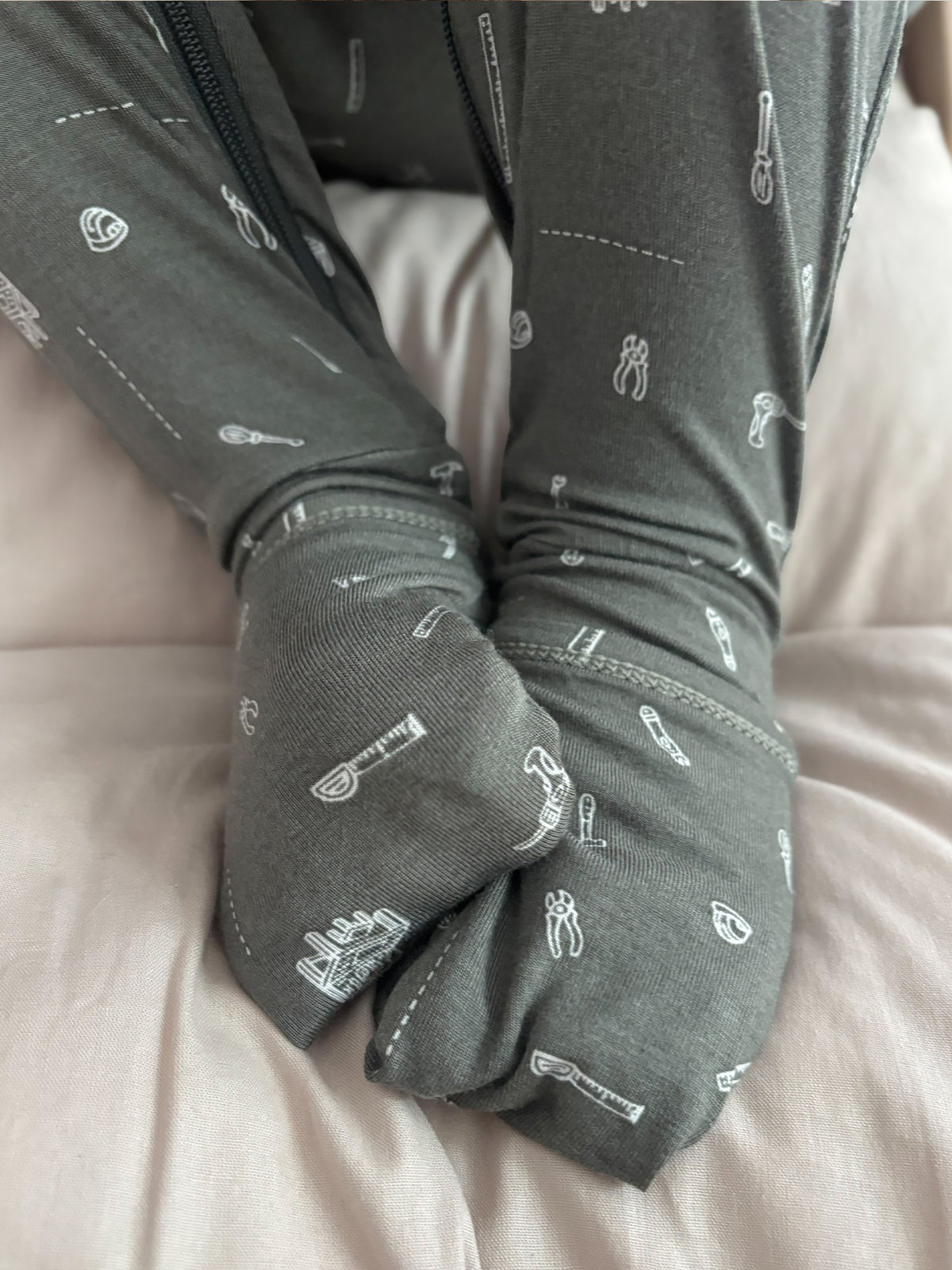 Convertible dark gray pajama with white tool icons, close-up of cuffed legs and zipper