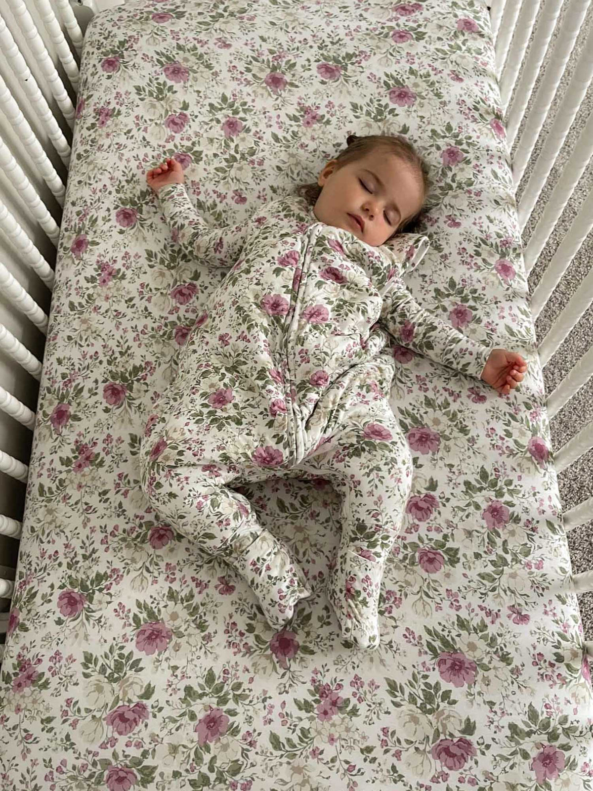 Floral crib sheet with scattered rose print in mauve and pink on light fabric