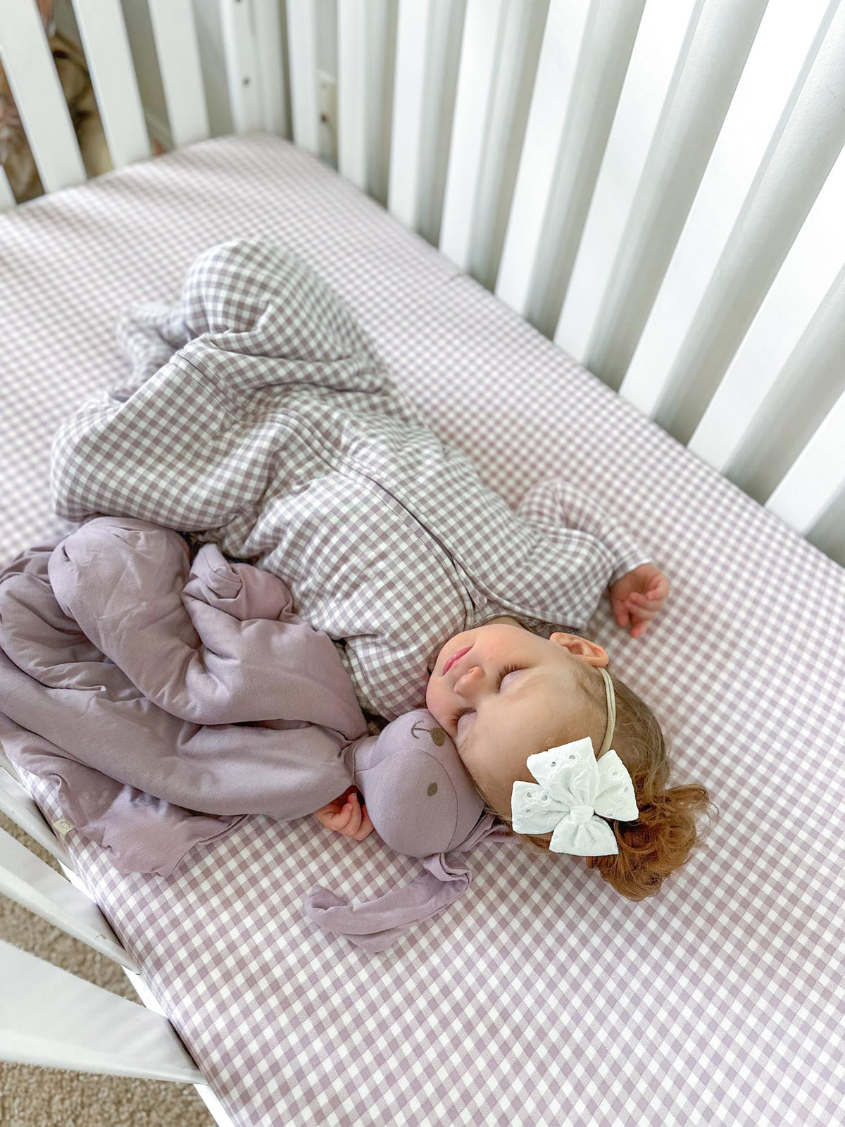 Lavender bunny lovey plush tucked beside a sleeping baby