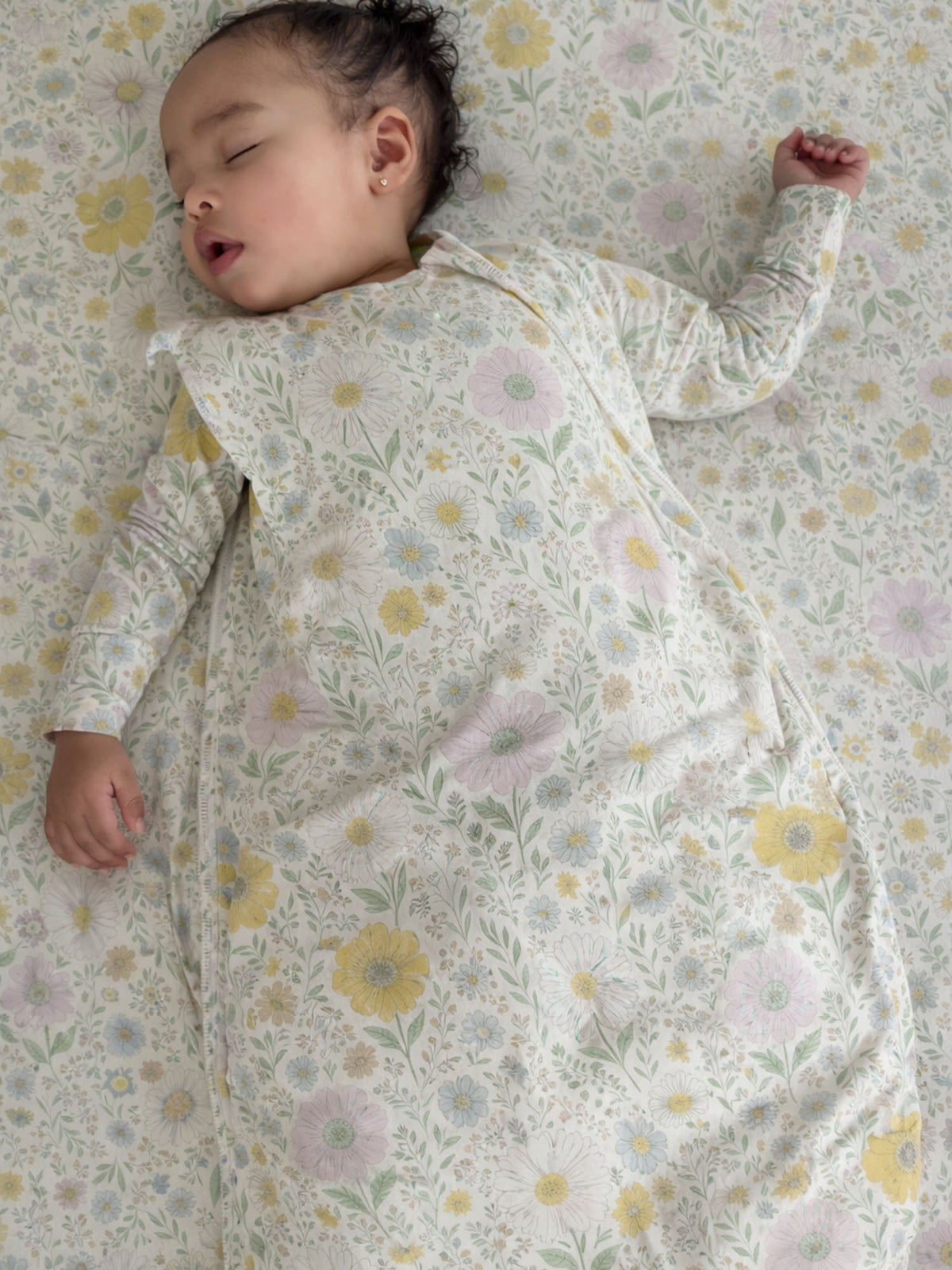 Infant in a white floral sleep sack with long sleeves and rounded neckline