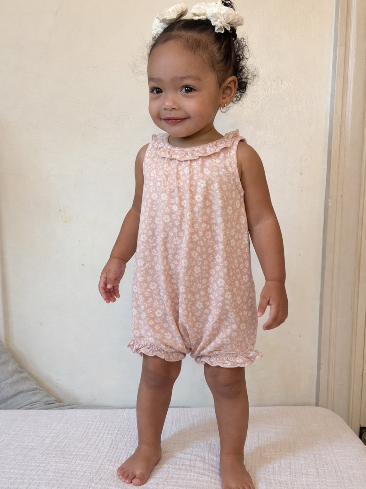 Light pink floral bubble romper with ruffled neck and loose bubble-leg fit