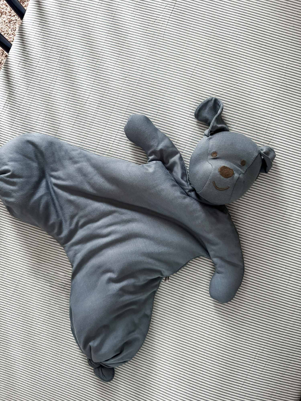Dusky blue plush pup lovey with long ears and stitched face on padded blanket