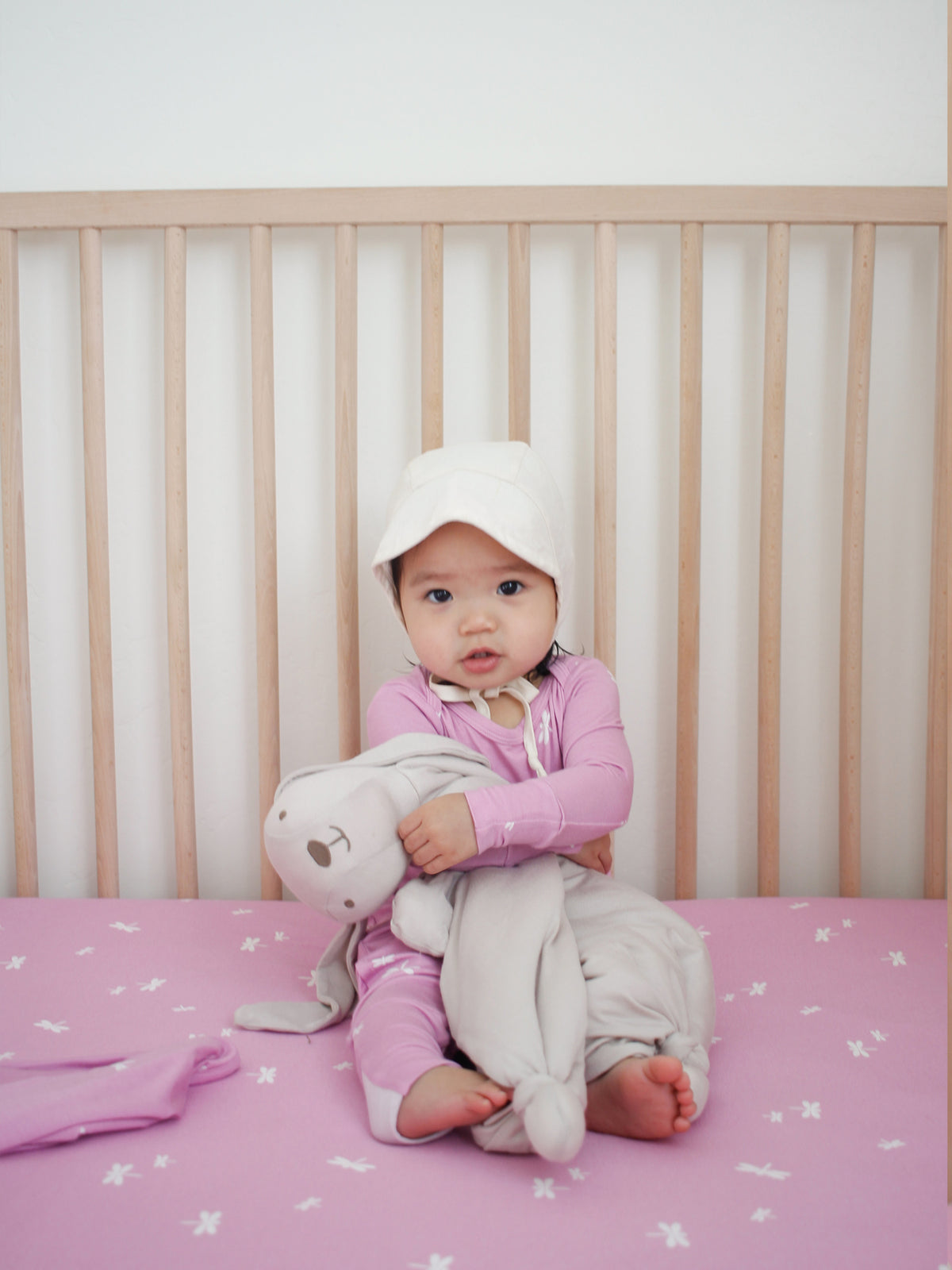 Pink hooded one-piece pajama with firefly print, holding plush toy