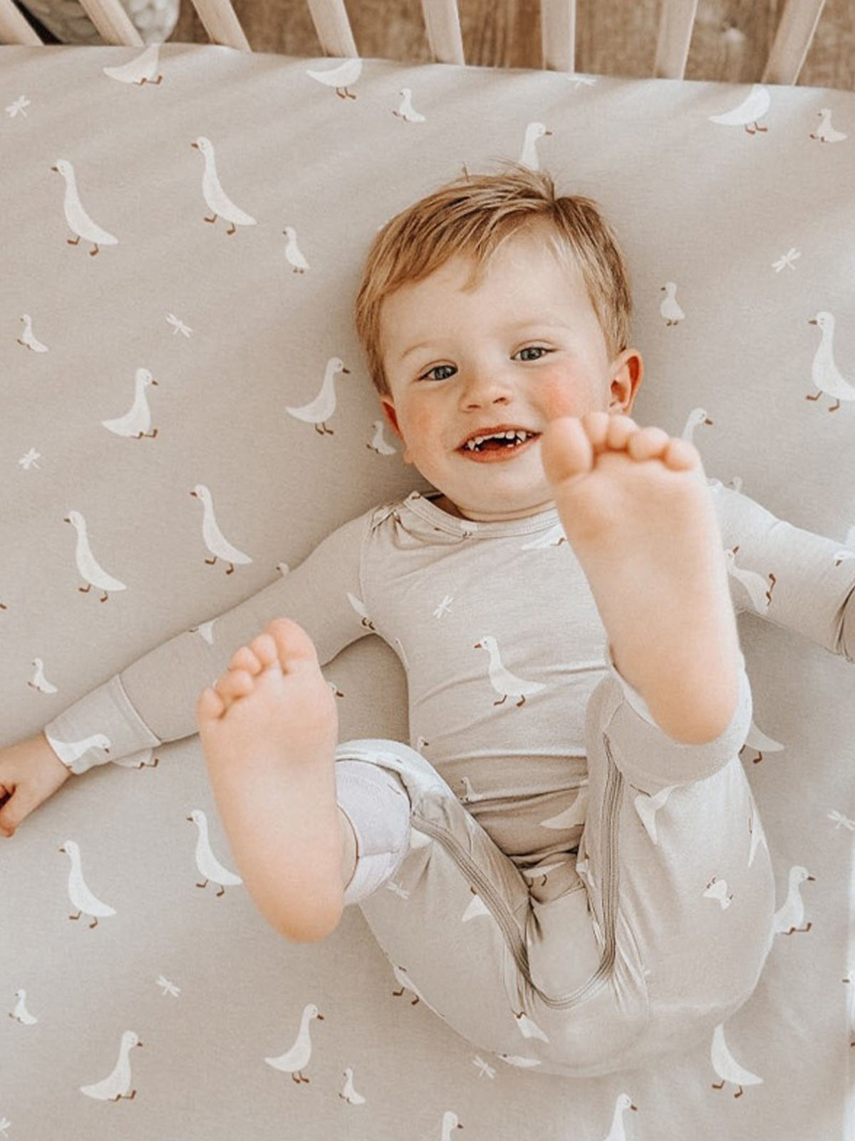 Light taupe fitted crib sheet covered in small white geese