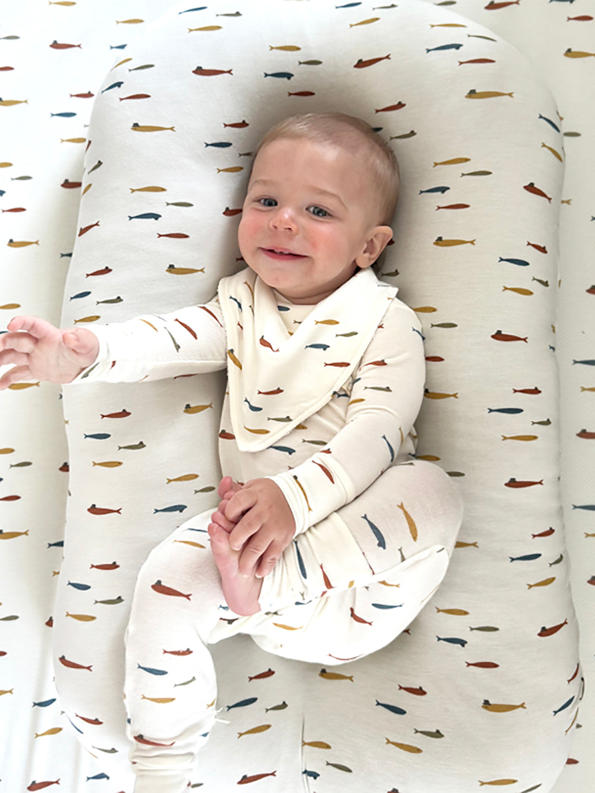 Fish-themed changing pad cover, cream fabric with scattered fish and hat motifs