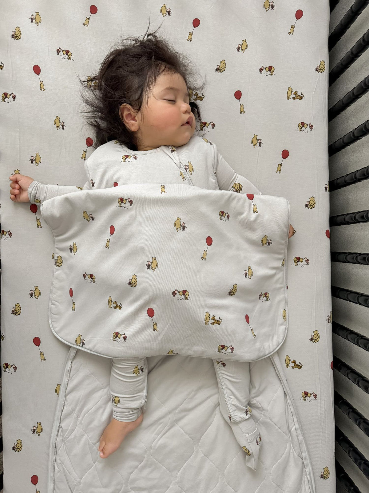 White baby sleep sack with Pooh character print, baby swaddled with arms out