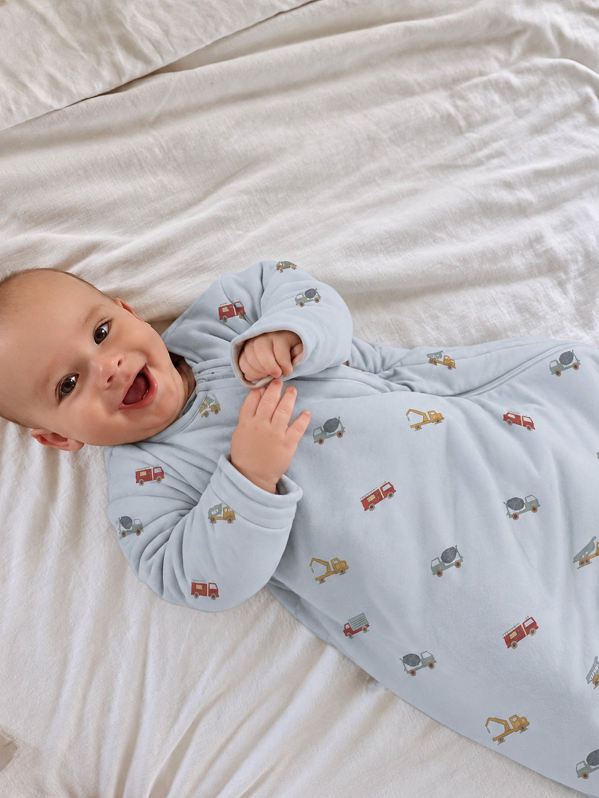 Light blue newborn sleep sack with long sleeves and small vehicle-print all over