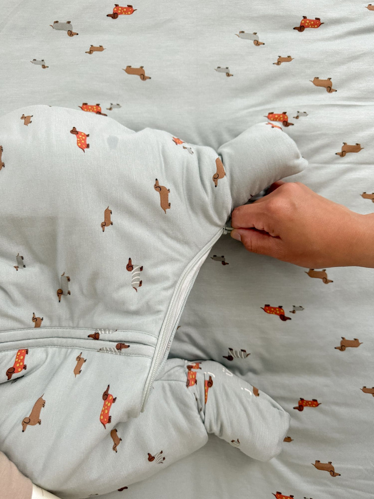 Light blue footie sleep sack close-up with dog print and front zipper seam