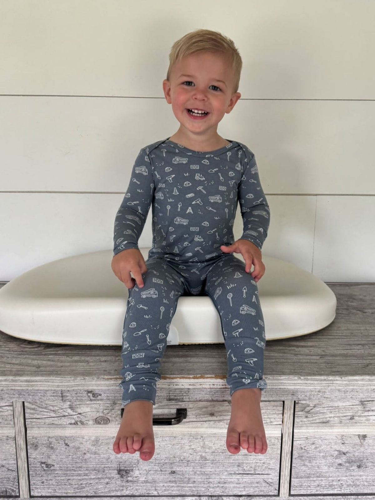 Blue construction-print long-sleeve pajama set on a seated child