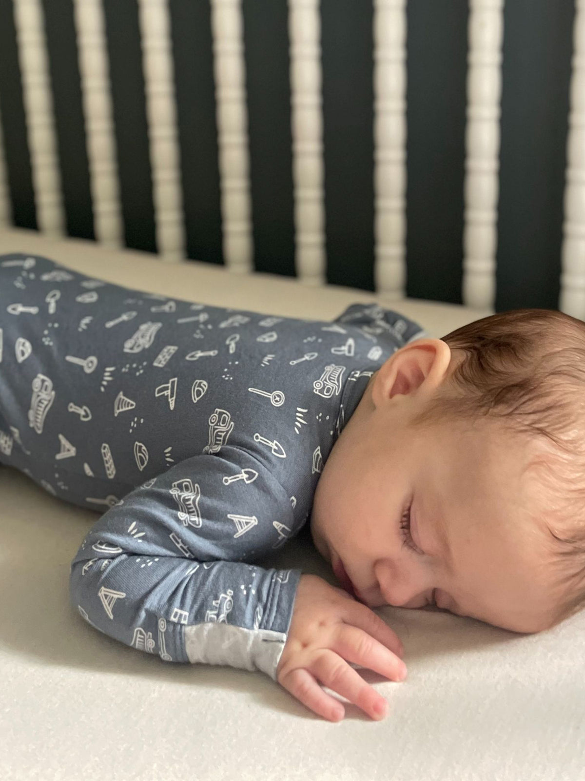 Blue construction-print long-sleeve pajamas on a sleeping child
