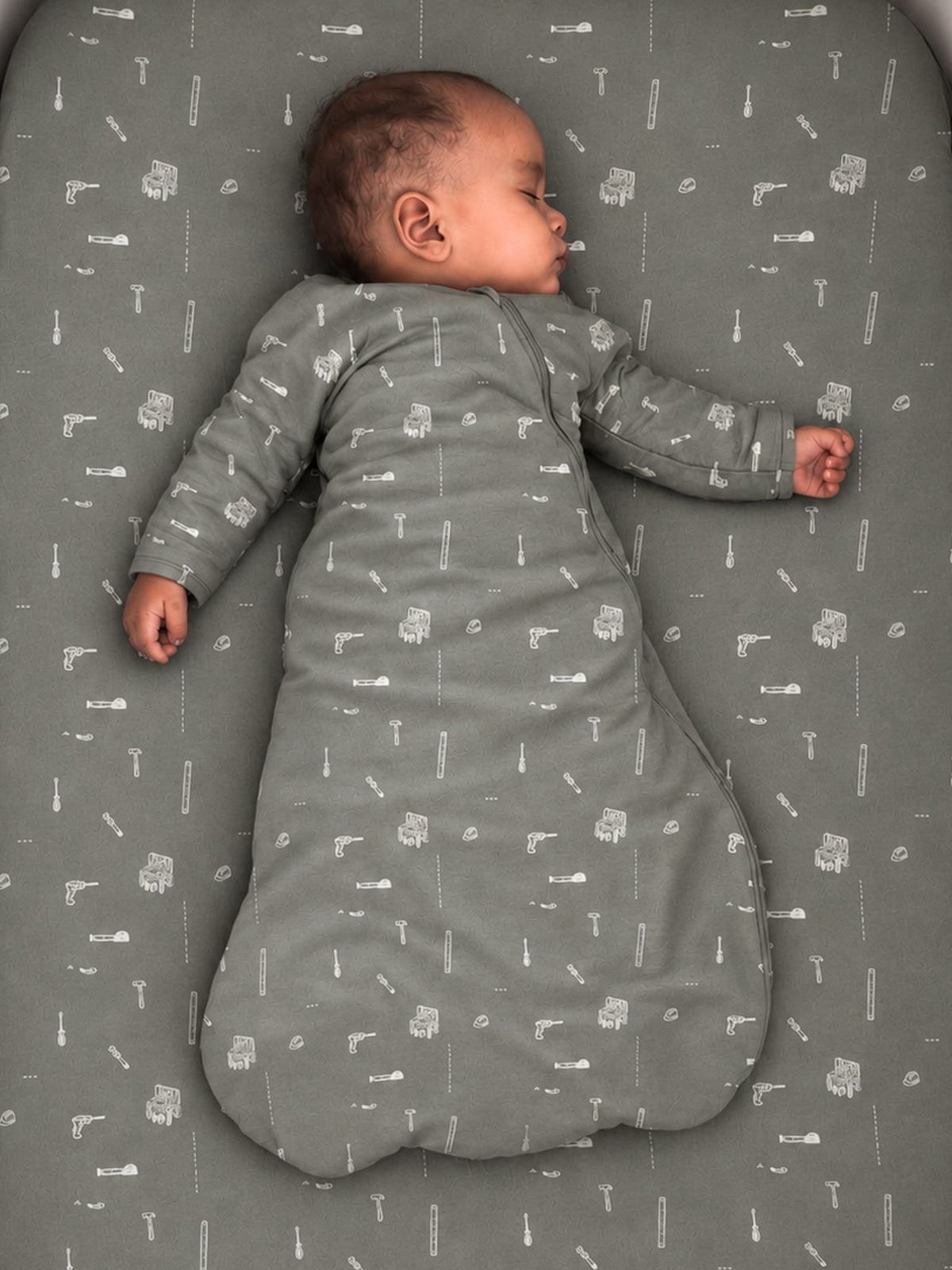 Long sleeve swaddle sack in dark gray with tool print, baby side view, 2.5 TOG
