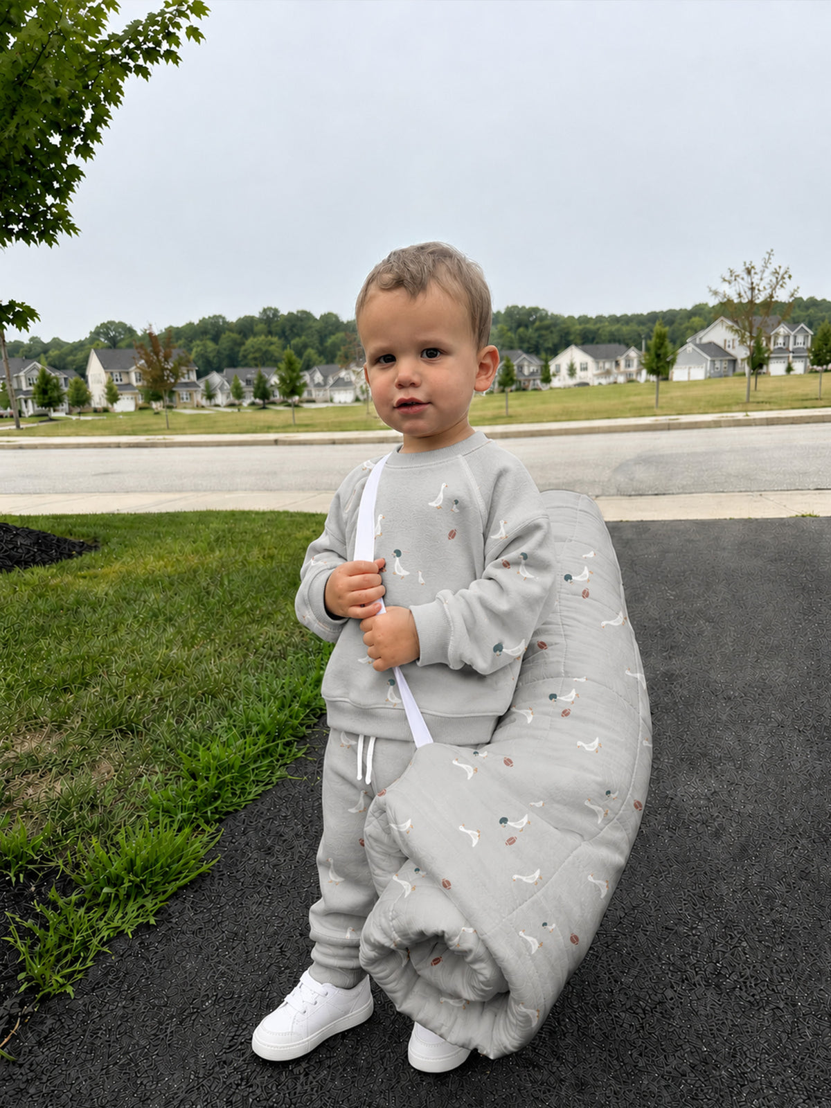 Gray baby nap mat with goose and football pattern, secured around a child outdoors