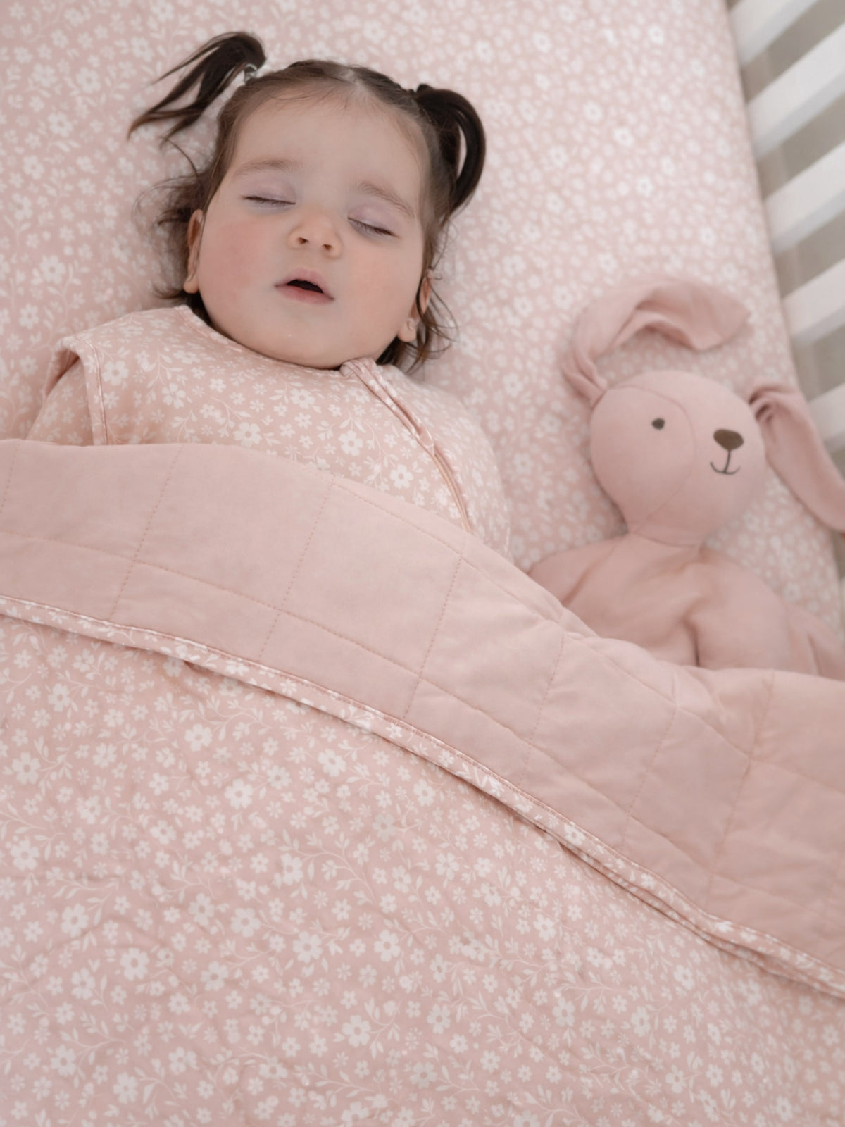 Pink floral baby blanket with quilted edge and soft satin trim, draped