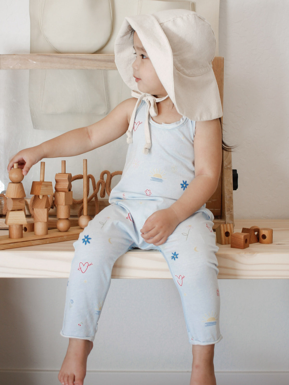 Light blue tank romper with colorful allover icons and ankle-length legs