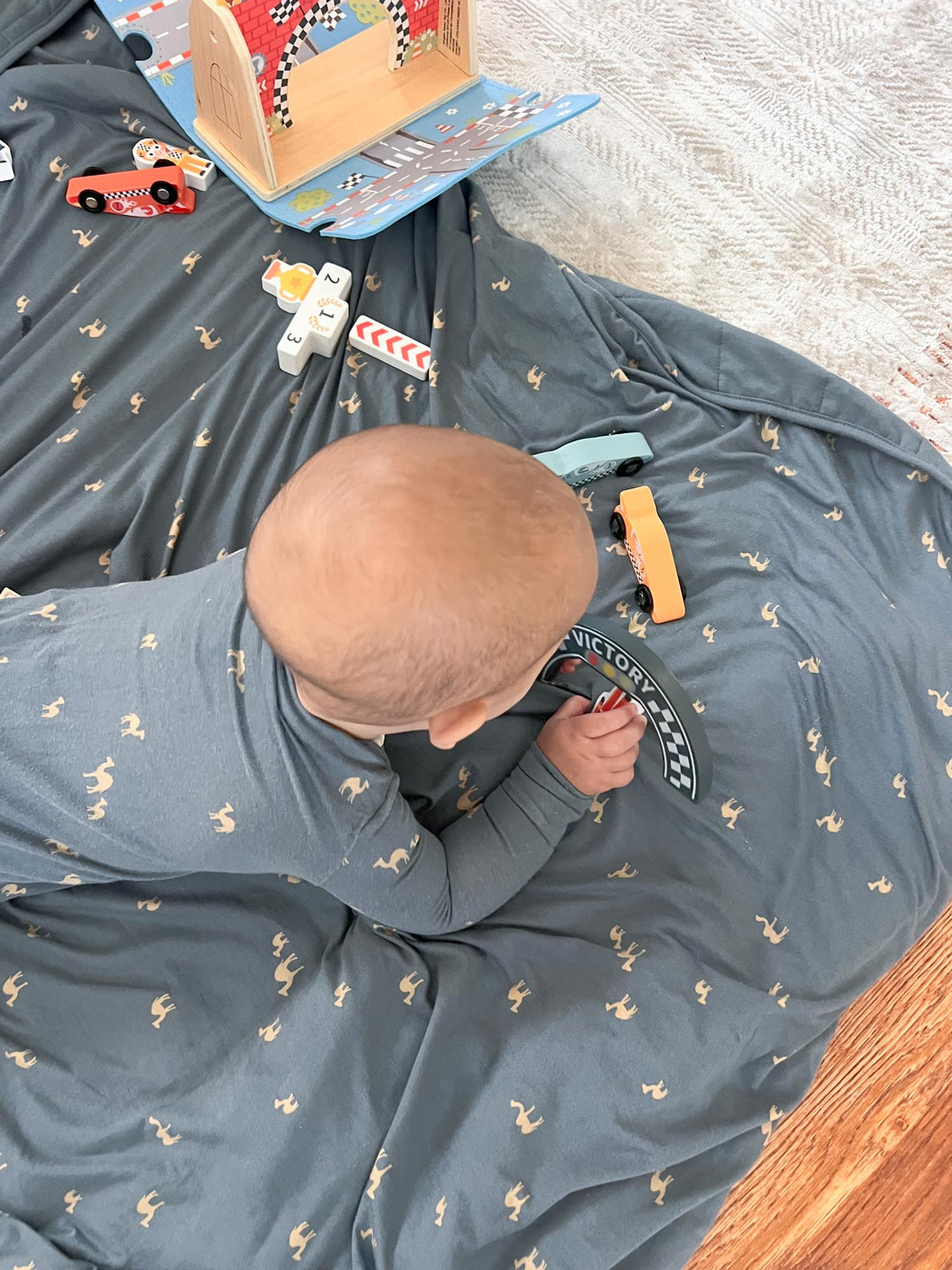 Dark blue camel-pattern play blanket with attached activity book and toys