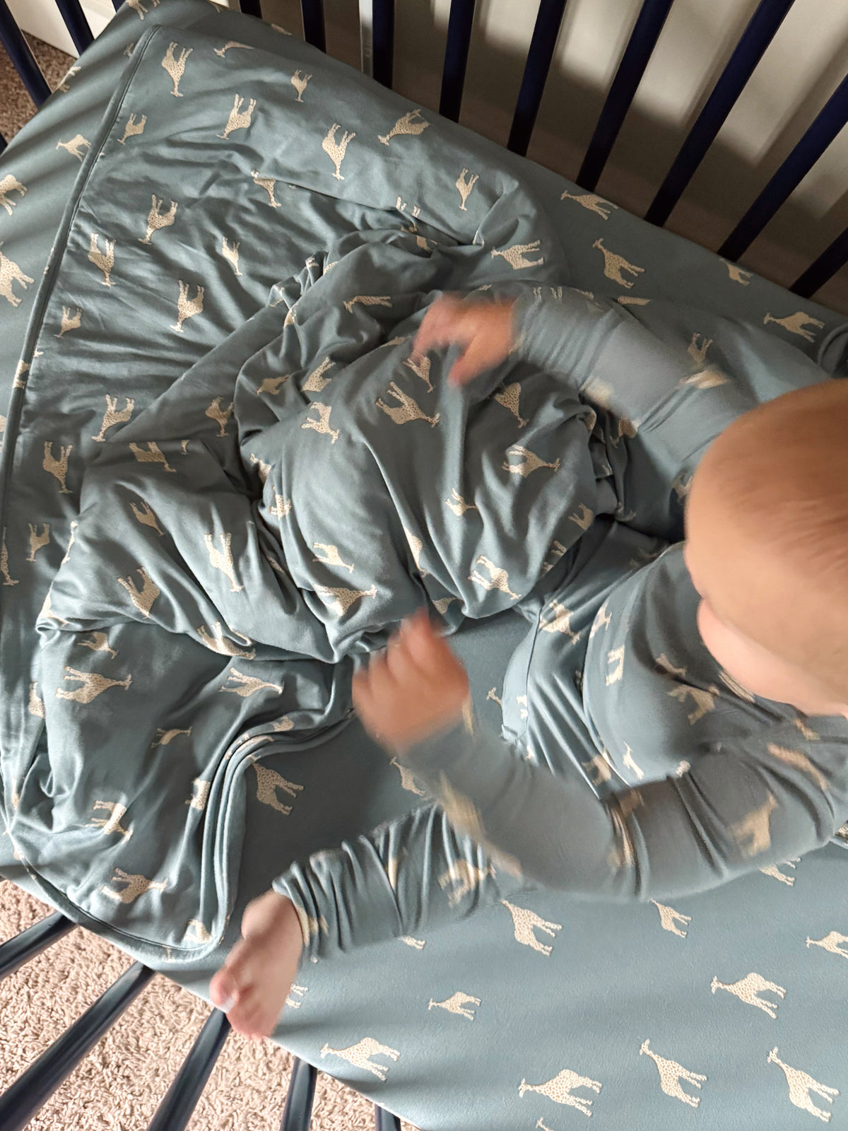 Crib sheet laid flat in teal with beige giraffe print and gathered corners