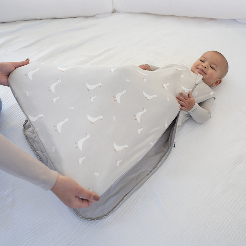Light gray baby sleep sack with allover white duck pattern, front opening and zipper trim