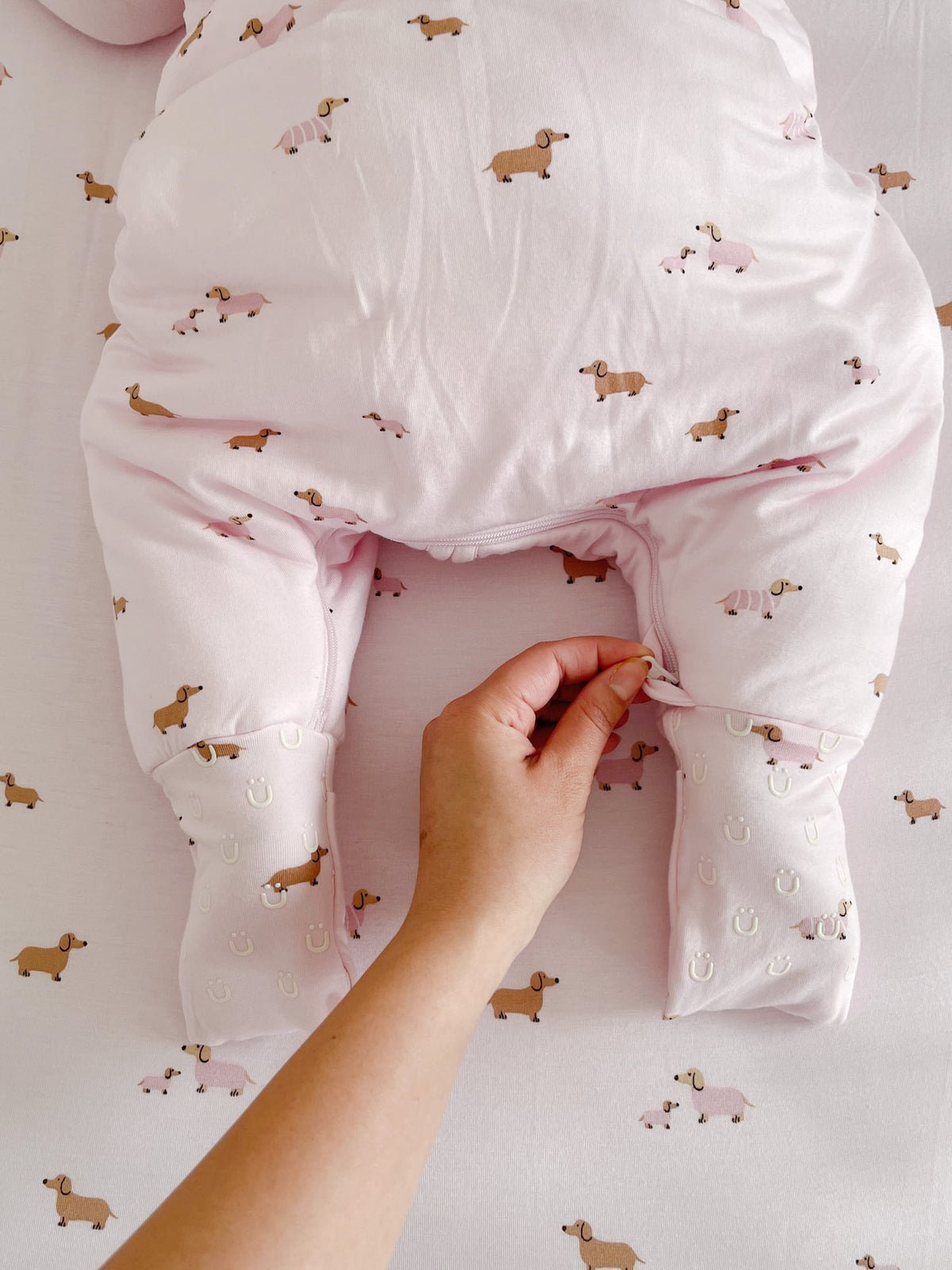 Pink dog-print footie sleep sack close-up with zipper and snap-style cuffs