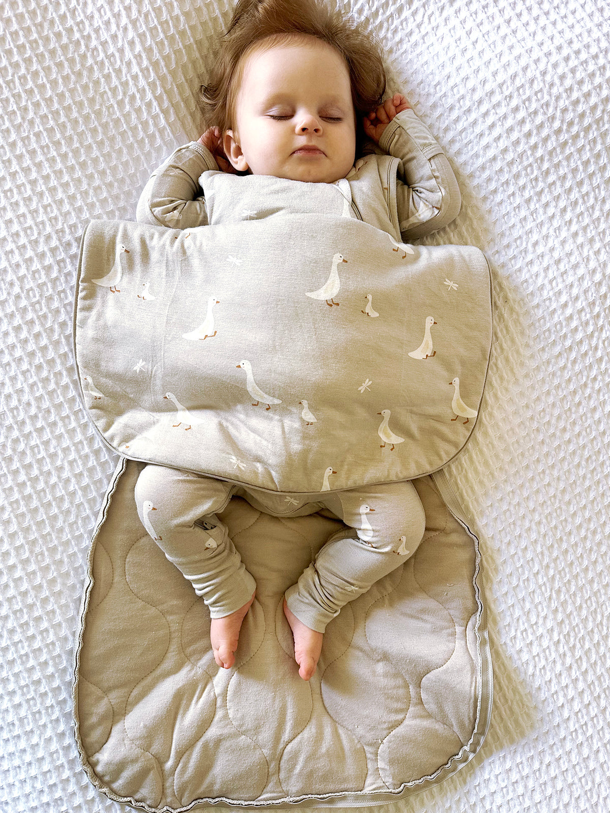 Beige transitional swaddle sleep sack with white goose print and wrap-style arms