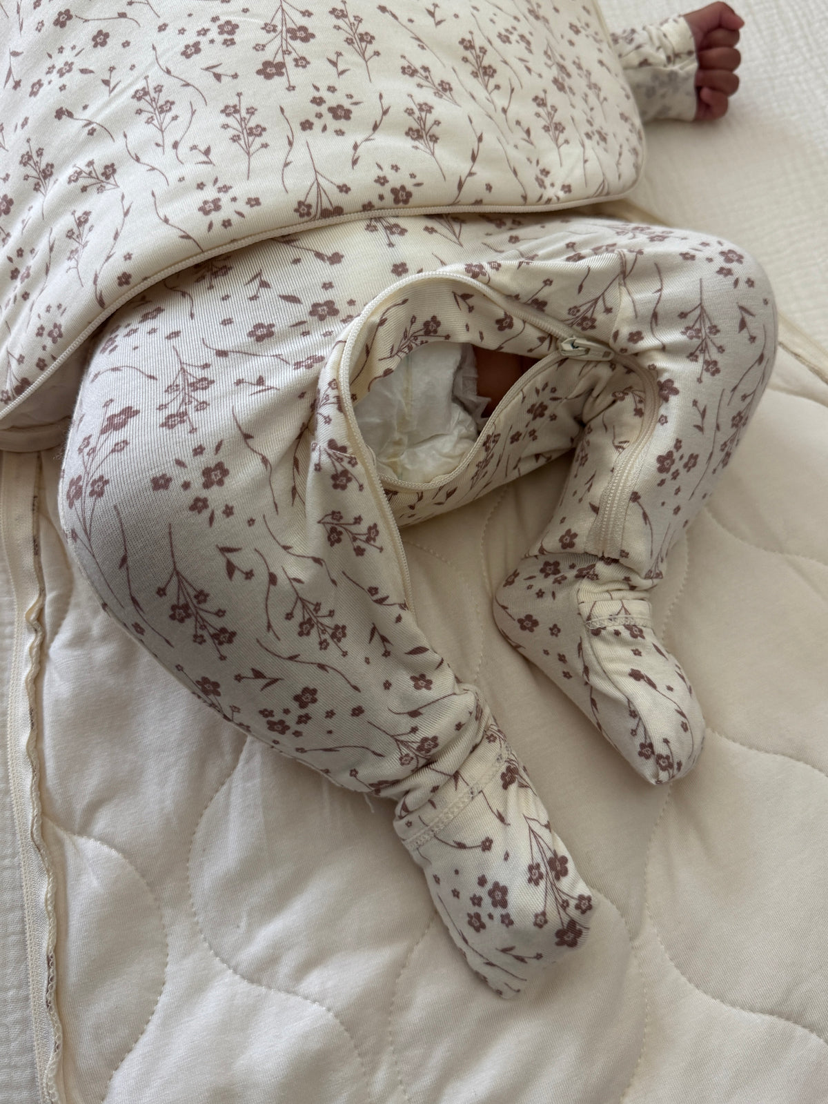 Cream swaddle sleep sack with small floral print, inner fold cuff, zip opening