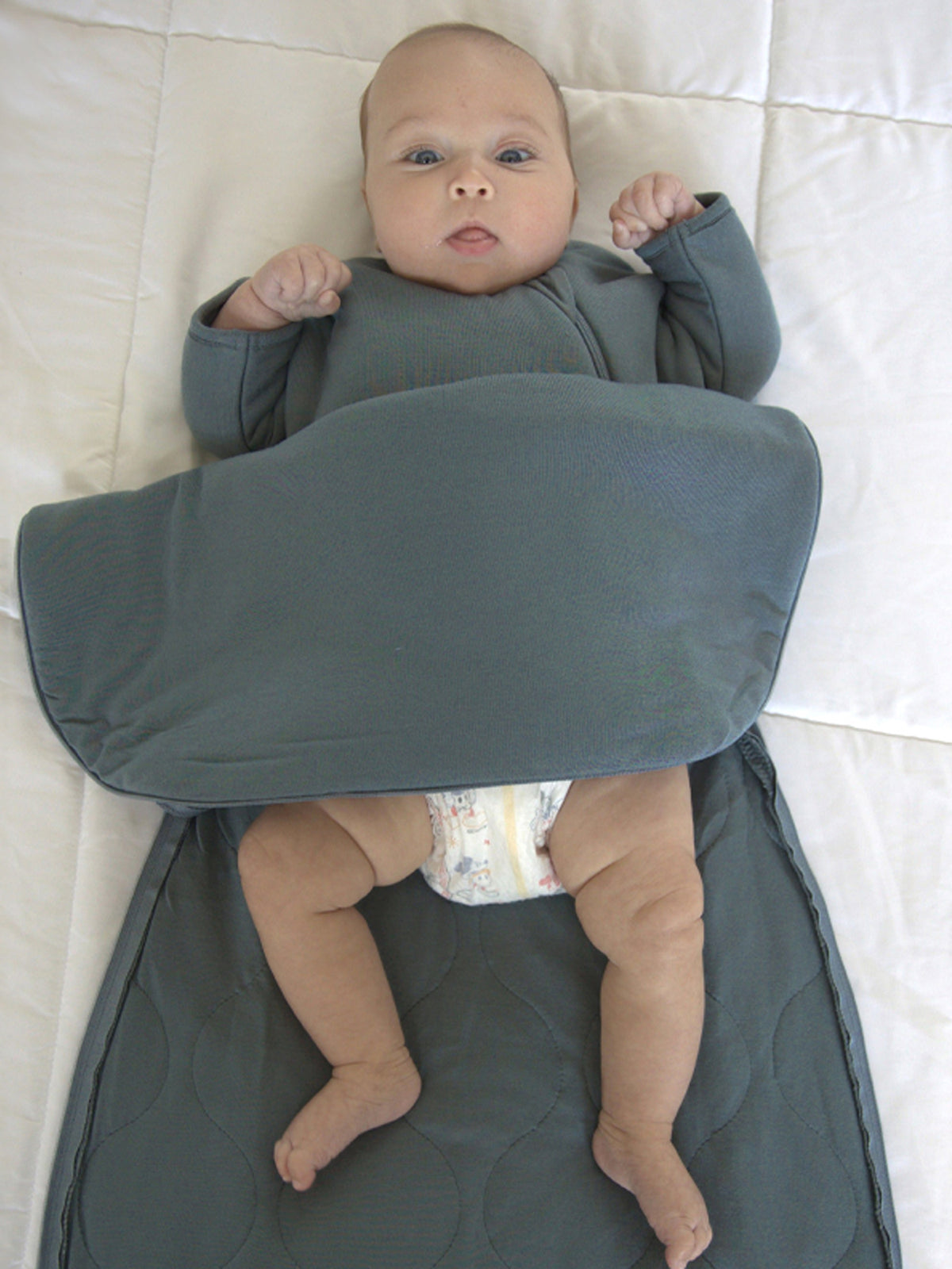 Dark teal long-sleeve swaddle sack with zipper, wrap-style top around baby