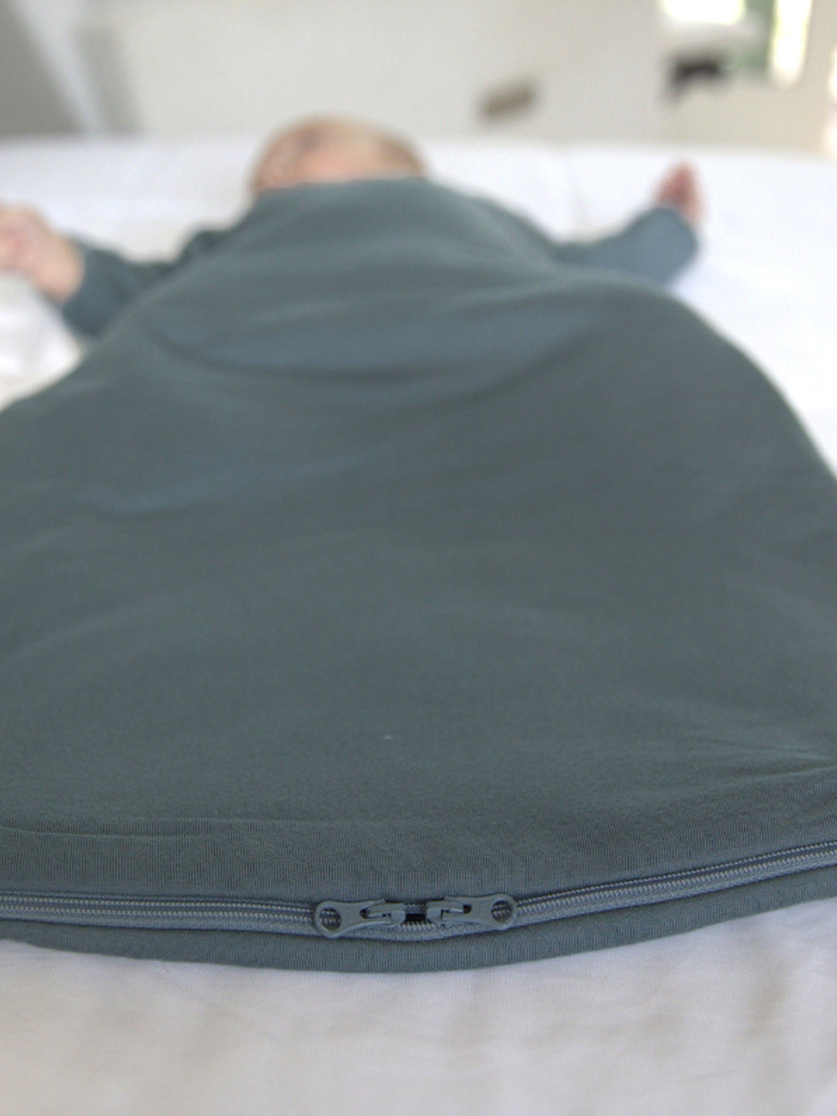 Dark teal swaddle sack with front zipper and stitched seam details
