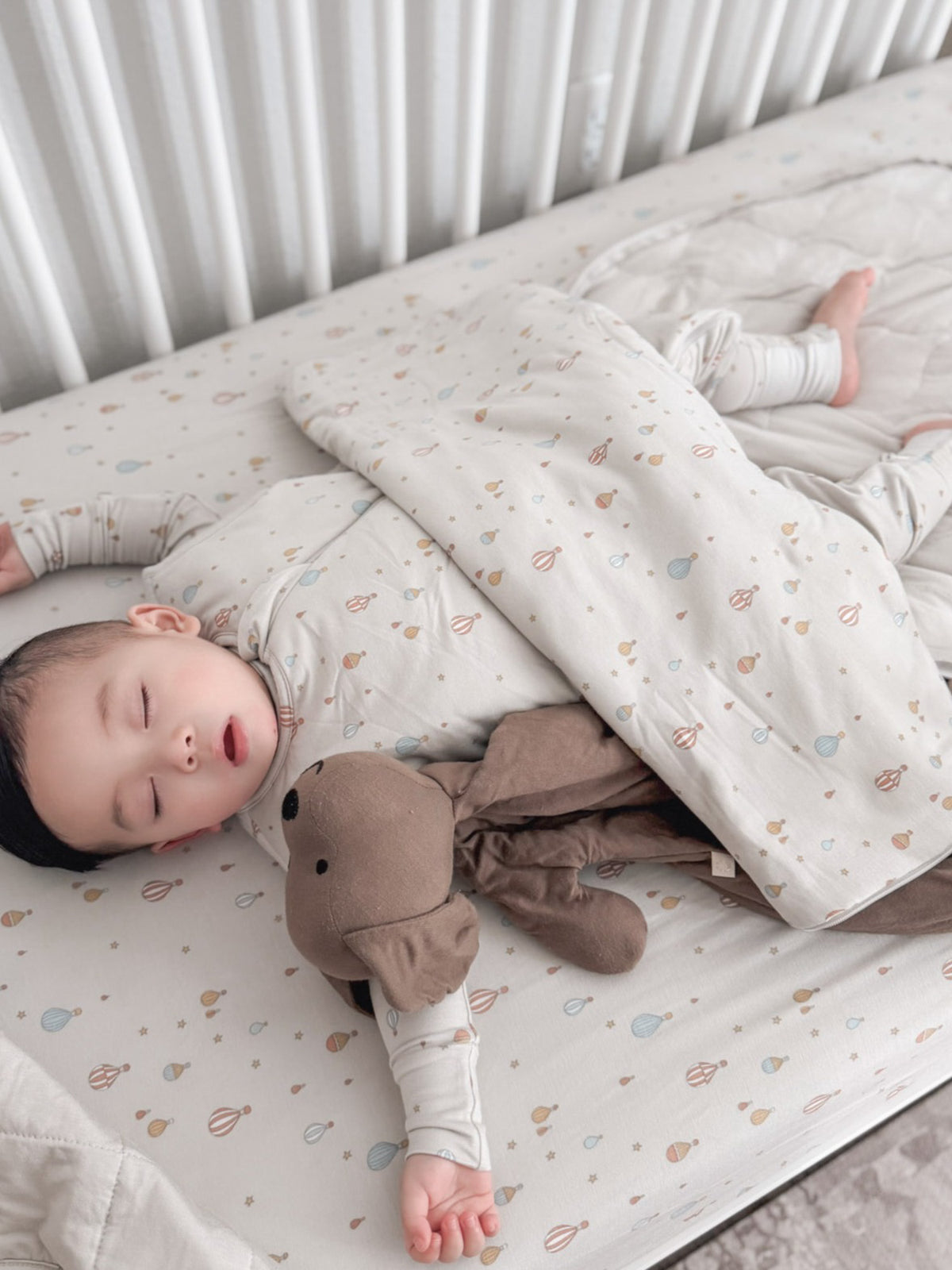 1.0 TOG sleep sack, cream with multicolor planet print, worn by sleeping baby