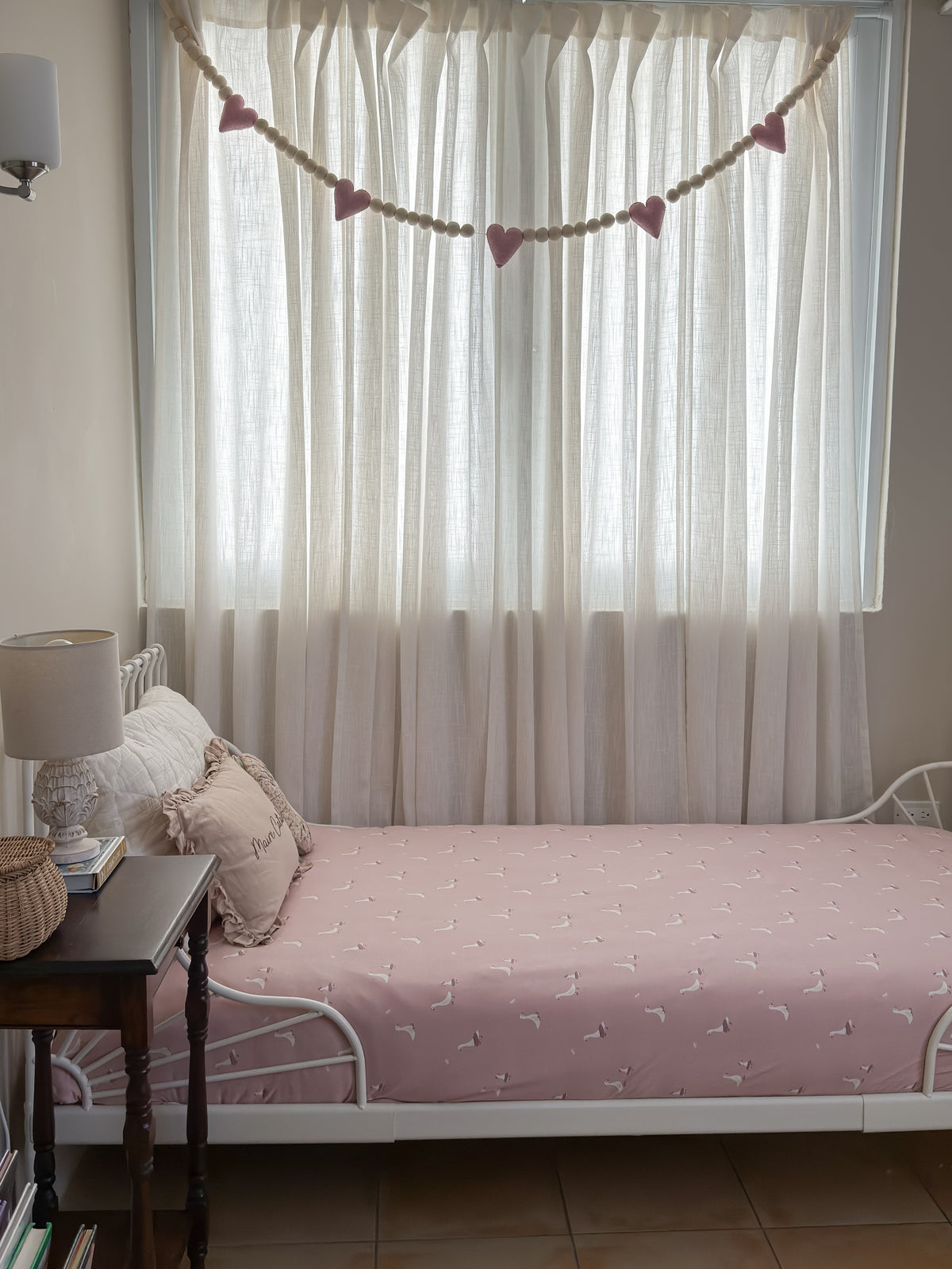 Pink blanket with white bird pattern, twin size, laid on bed