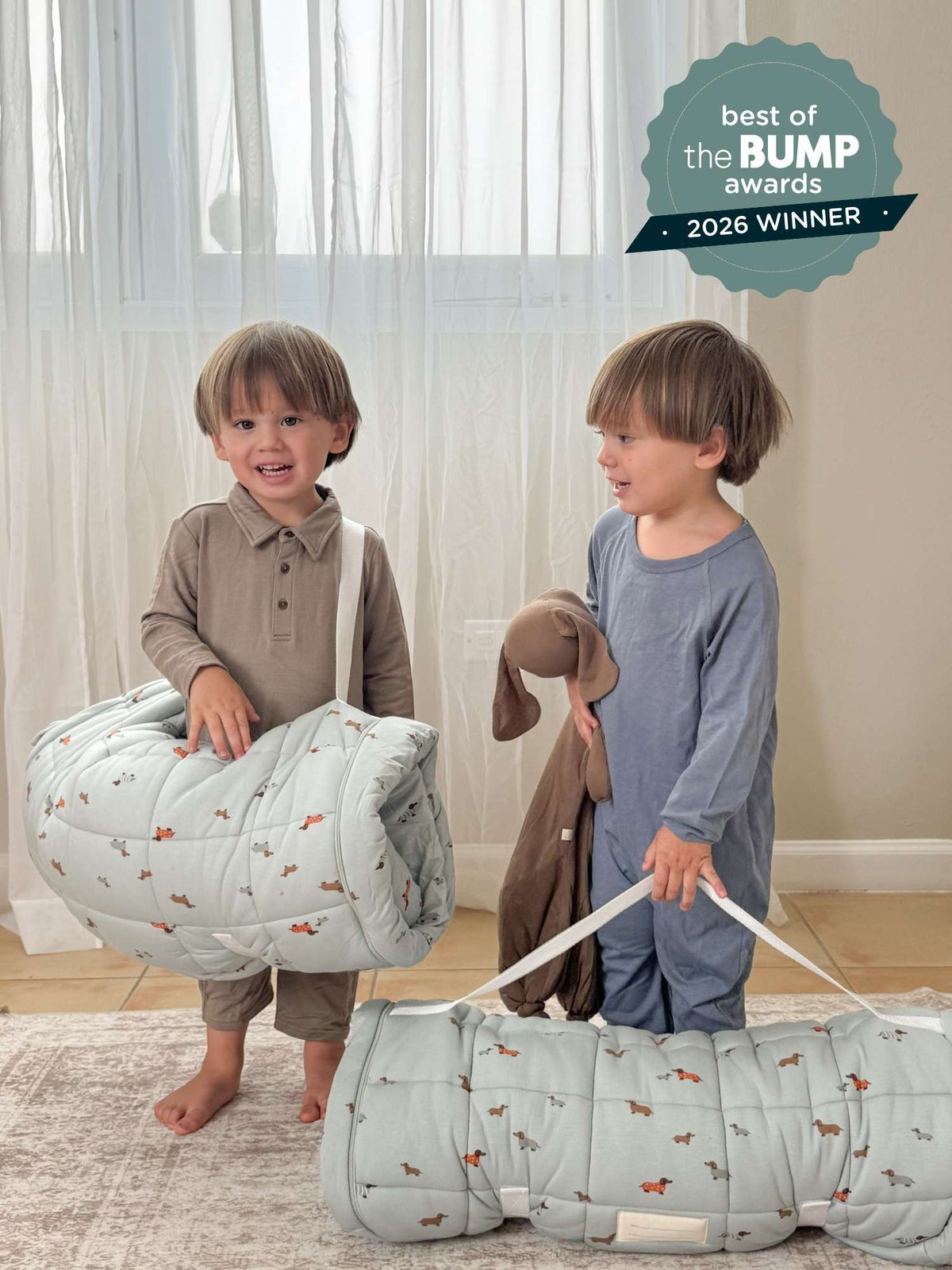 Folded light blue dog-print nap mat with straps, held by two kids