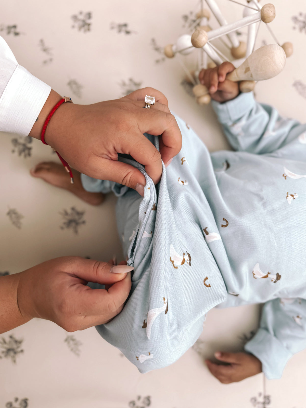 Light blue fleece jumpsuit with animal print, hands adjusting the front
