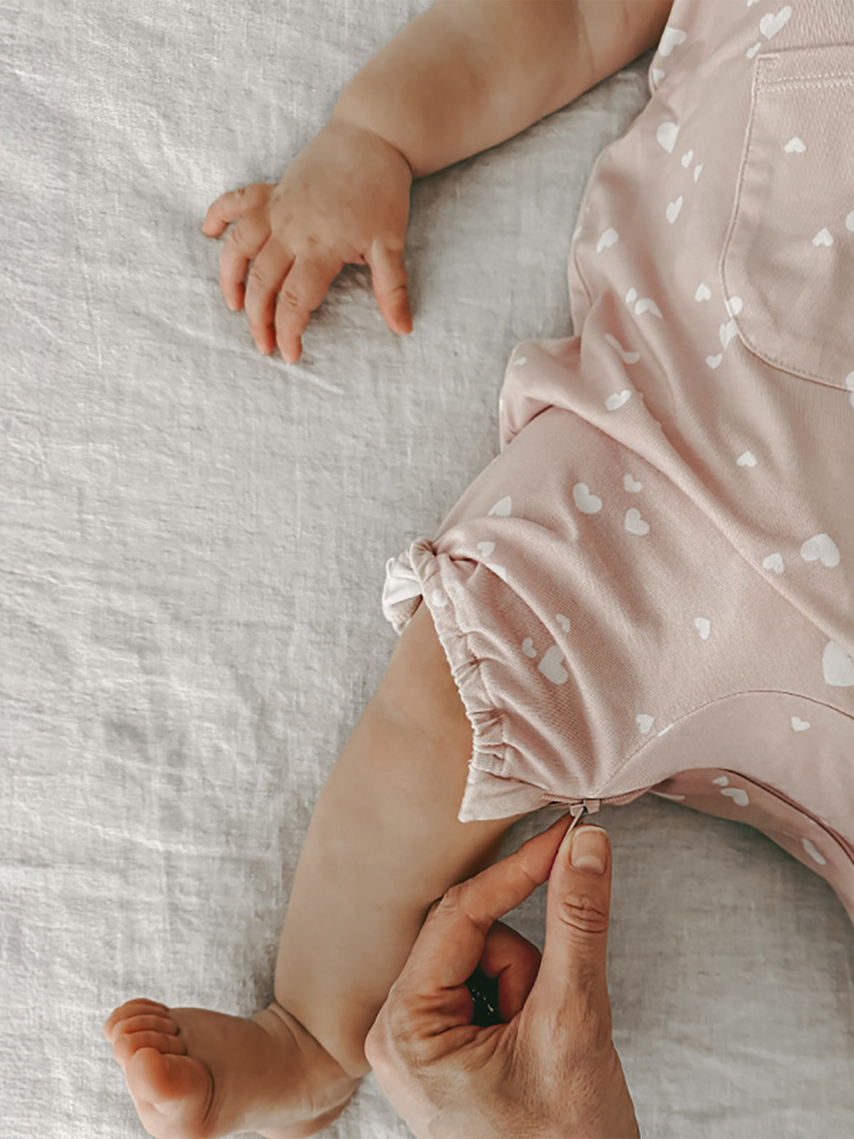 Light pink romper with white heart print, gathered ruffle shorts and elastic leg openings