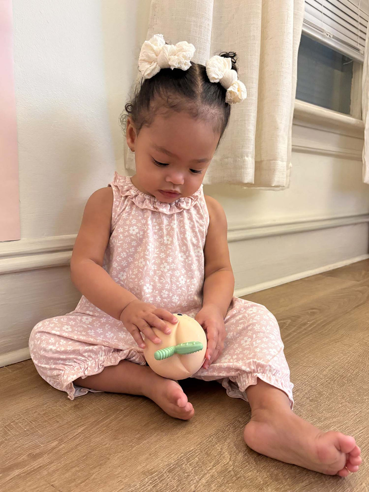 Light pink floral bubble romper on baby, sleeveless with ruffled collar and cuffs