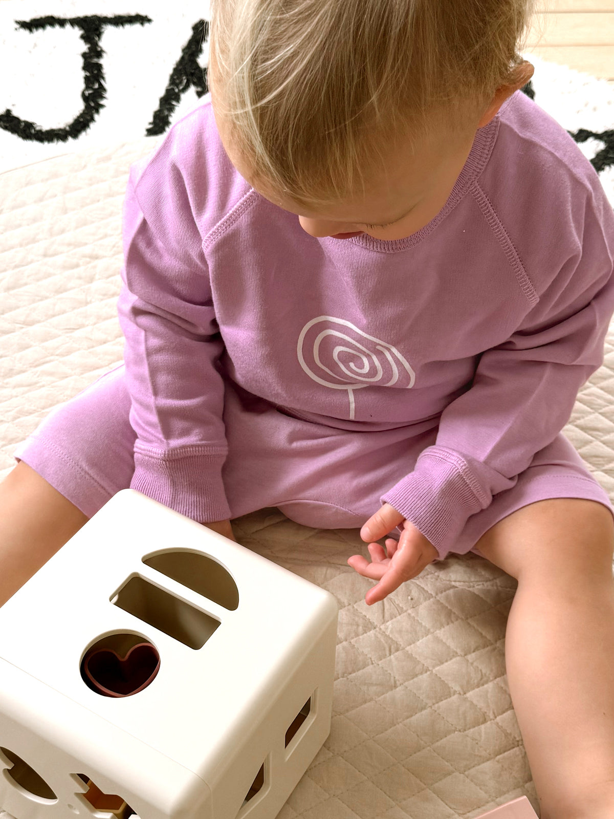 Lilac crewneck sweatshirt with white lollipop swirl graphic on the back