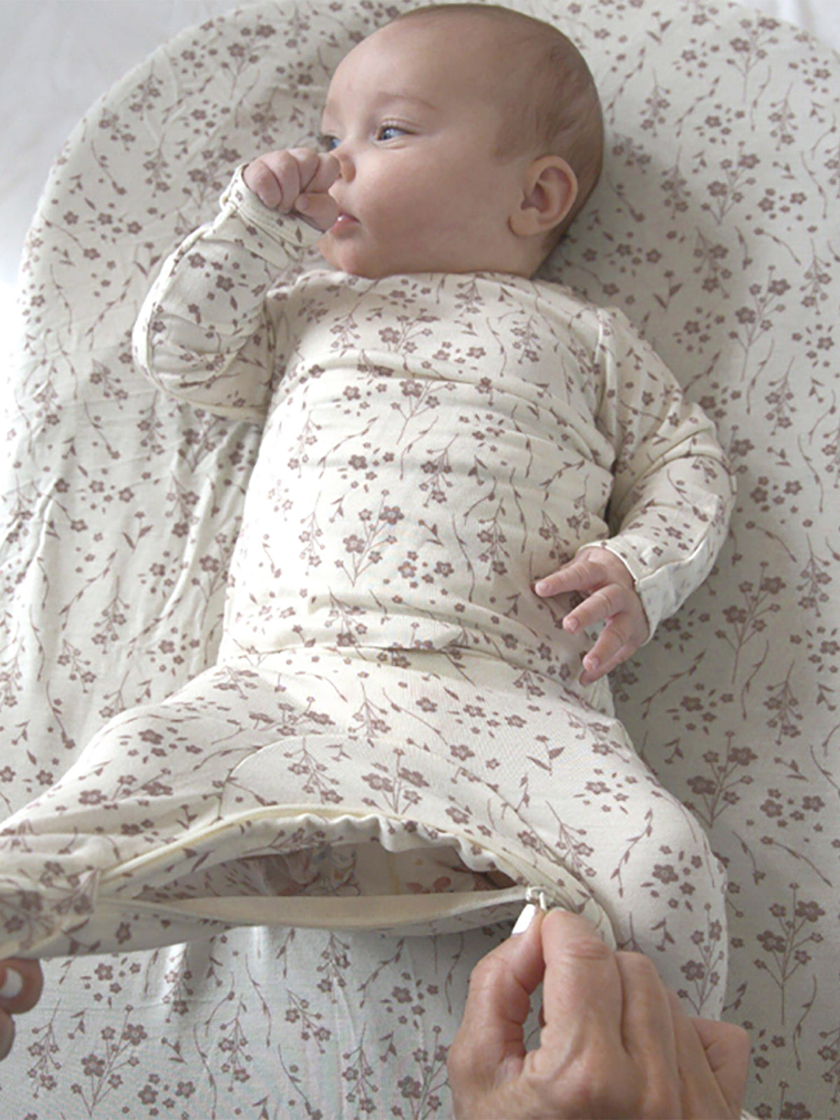 Cream floral two-piece footie set, long sleeves and foldover cuffs; baby lying