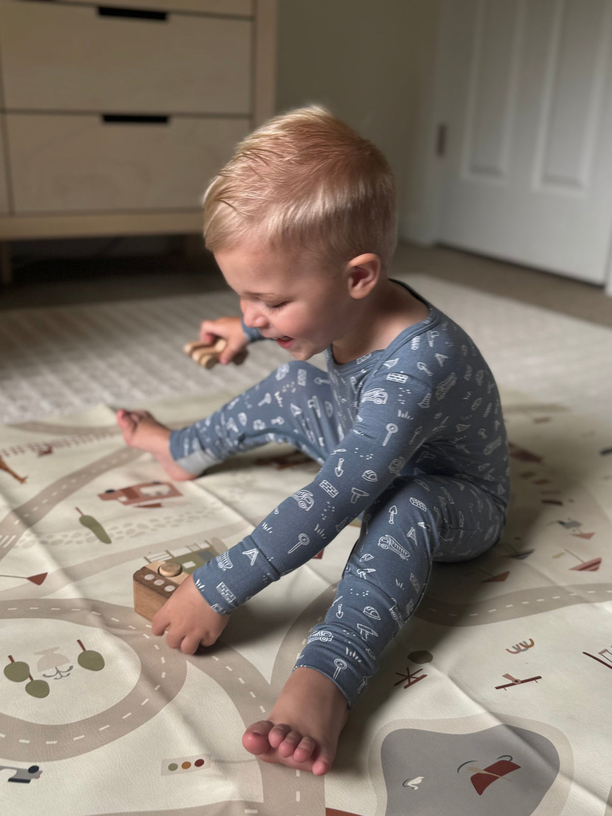 Blue construction-print long-sleeve pajamas while crawling on the floor