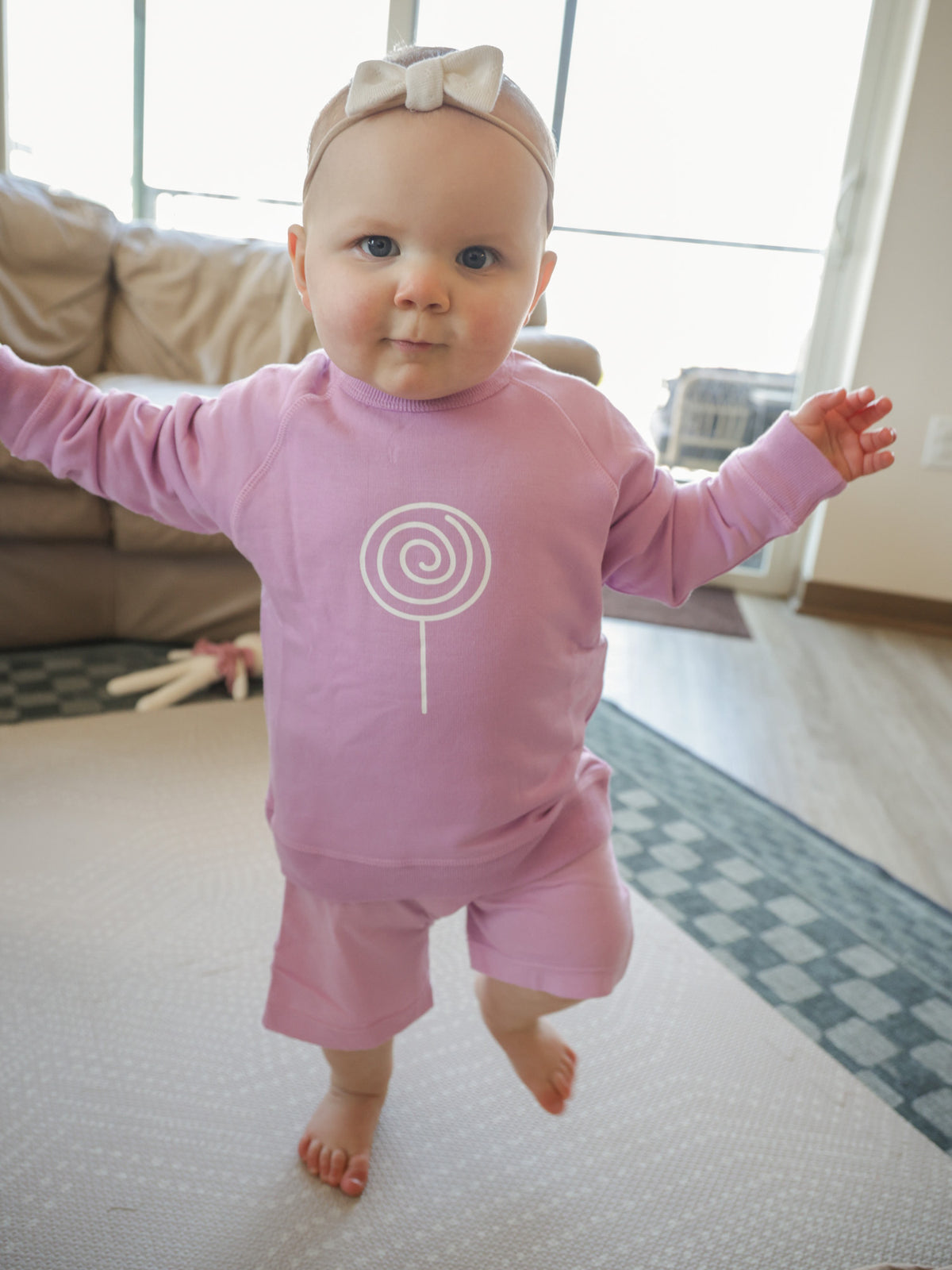 Lilac crewneck sweatshirt with white lollipop swirl logo on the front