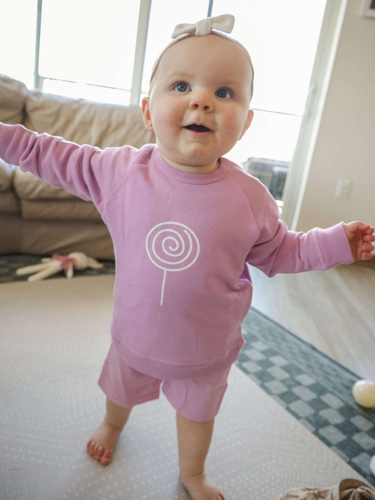 Lilac long-sleeve crewneck sweatshirt with white lollipop swirl logo