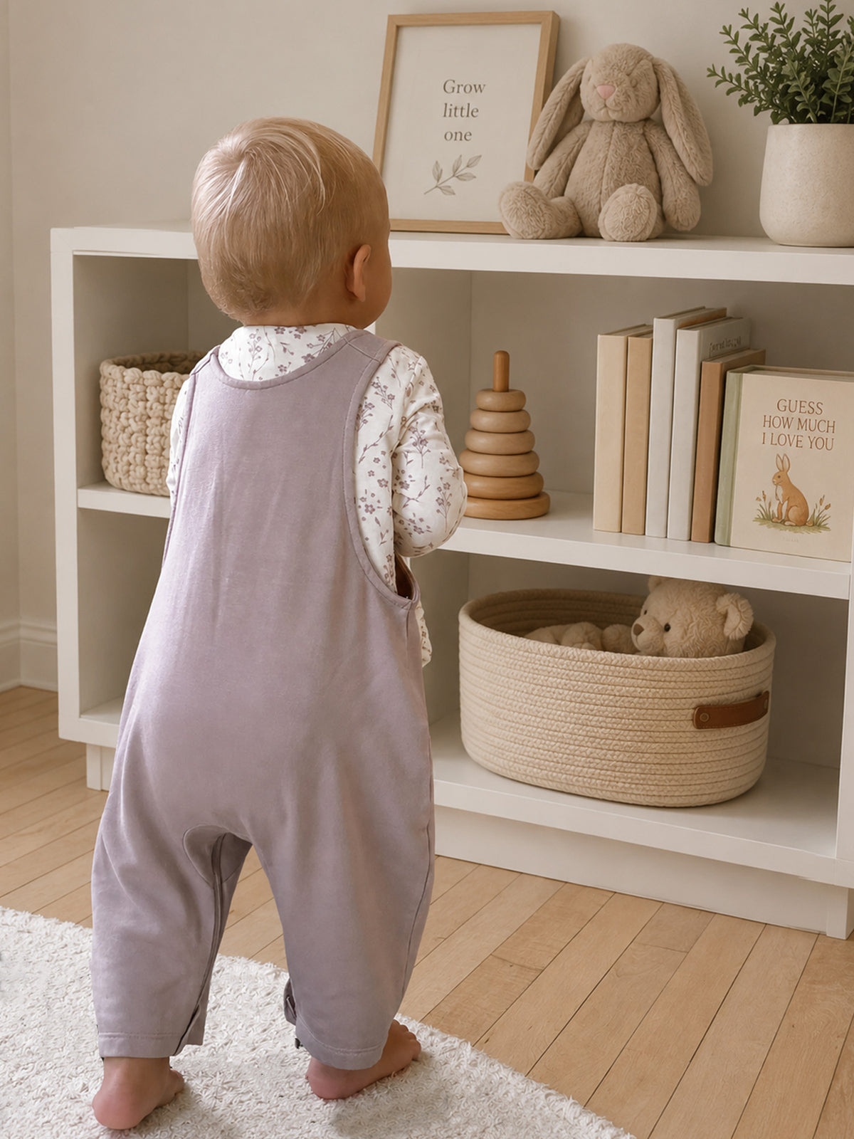 Light mauve fleece overalls worn over floral-print long sleeves, back view