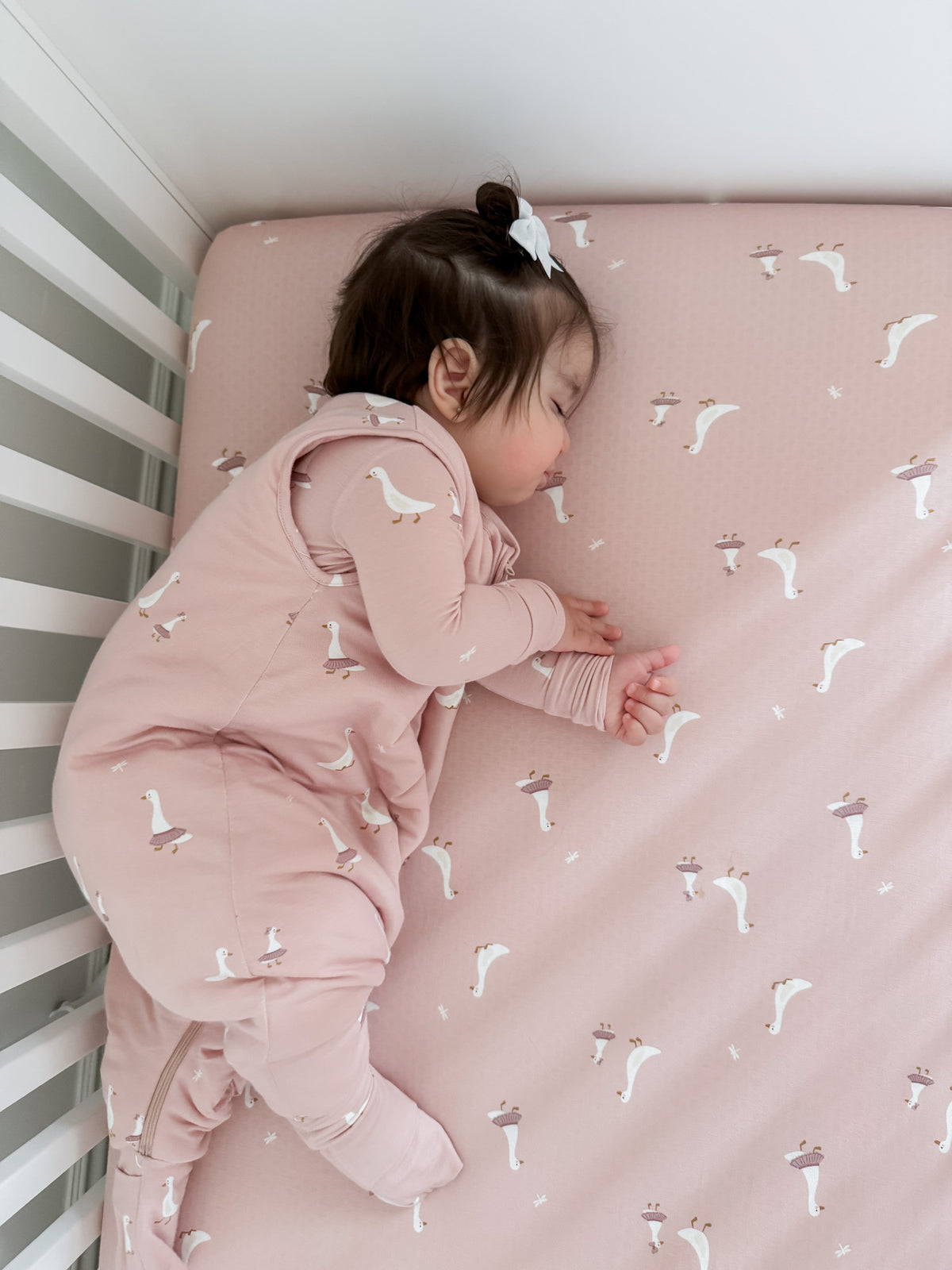 Pink footie sleep sack with duck print, worn by baby, long sleeves and feet