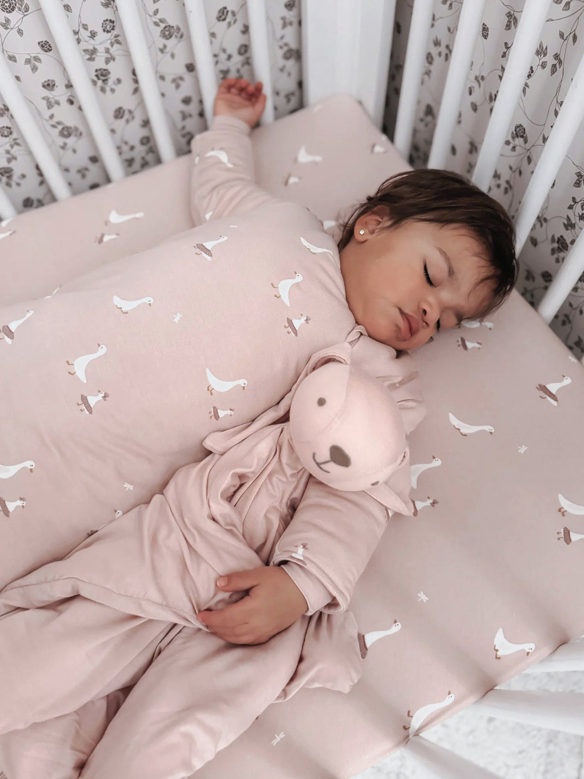 Light pink crib sheet with small white goose pattern, soft cotton