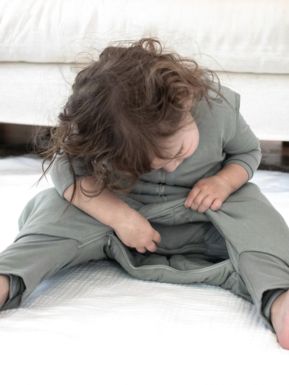 Sage green footie sleep sack with front zipper and long sleeves on a baby