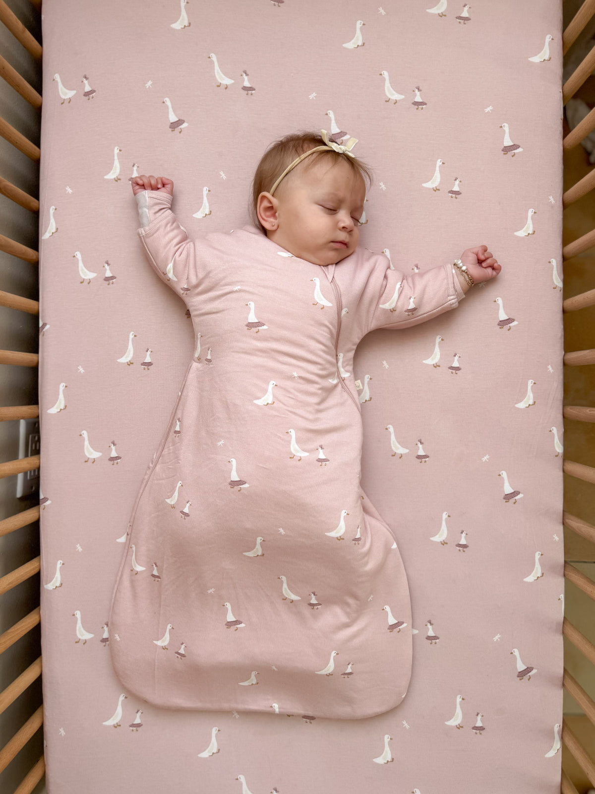 Dusty pink long-sleeve swaddle sack with white goose print, zip front