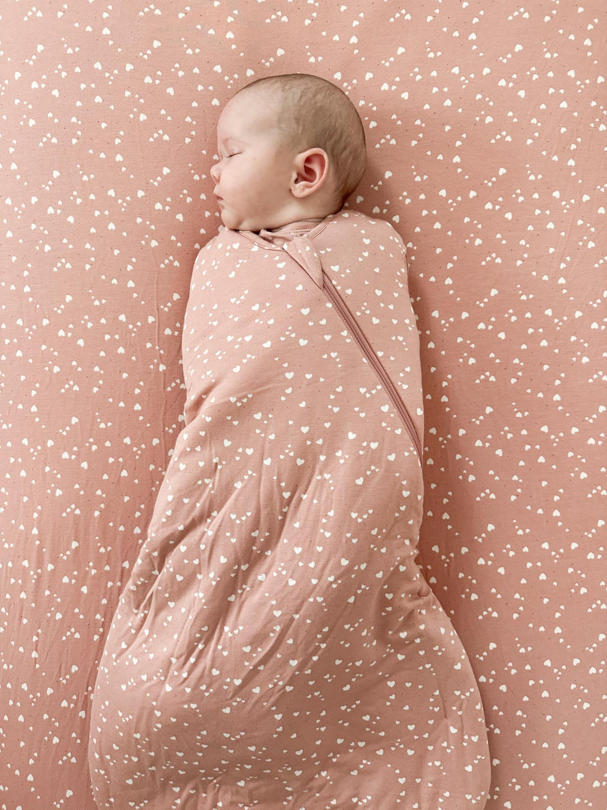 Pink 2.5 tog swaddle sleep sack with white hearts, wrapped long-sleeve design