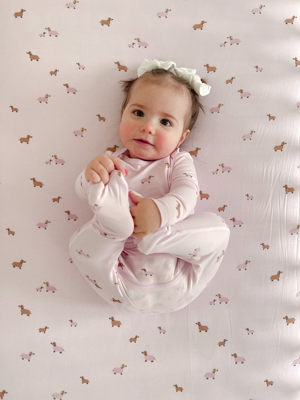 Crib sheet with small dog and animal print, pink and tan, light background