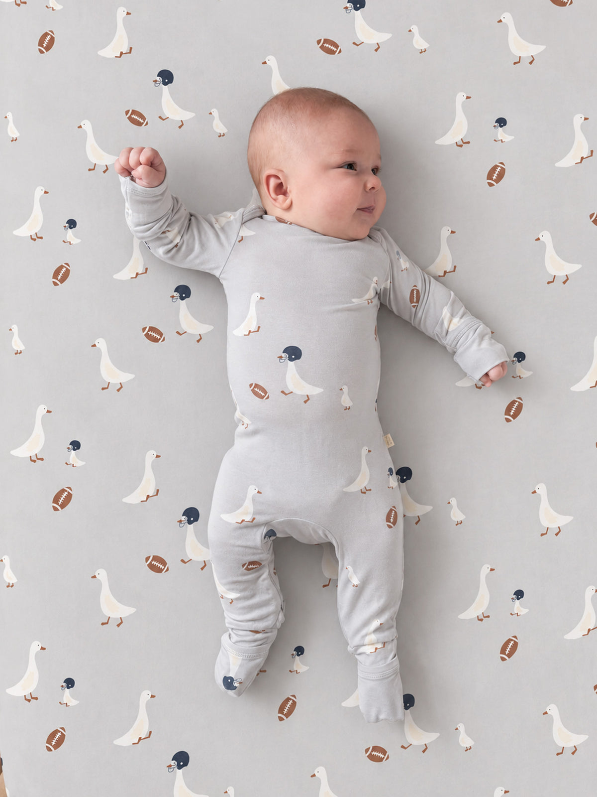 Light gray crib sheet with scattered white goose and football icons